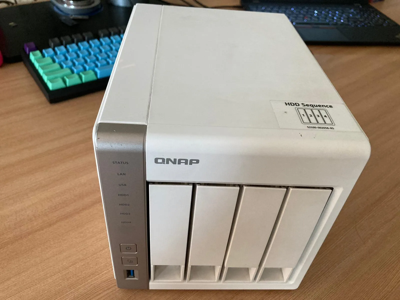 A picture of a white desk-top NAS (QNAP TS-459) on top of a wooden desk