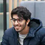 A picture of Humaid smiling, not while looking at the camera. Possibly in a discussion with people off-screen.
